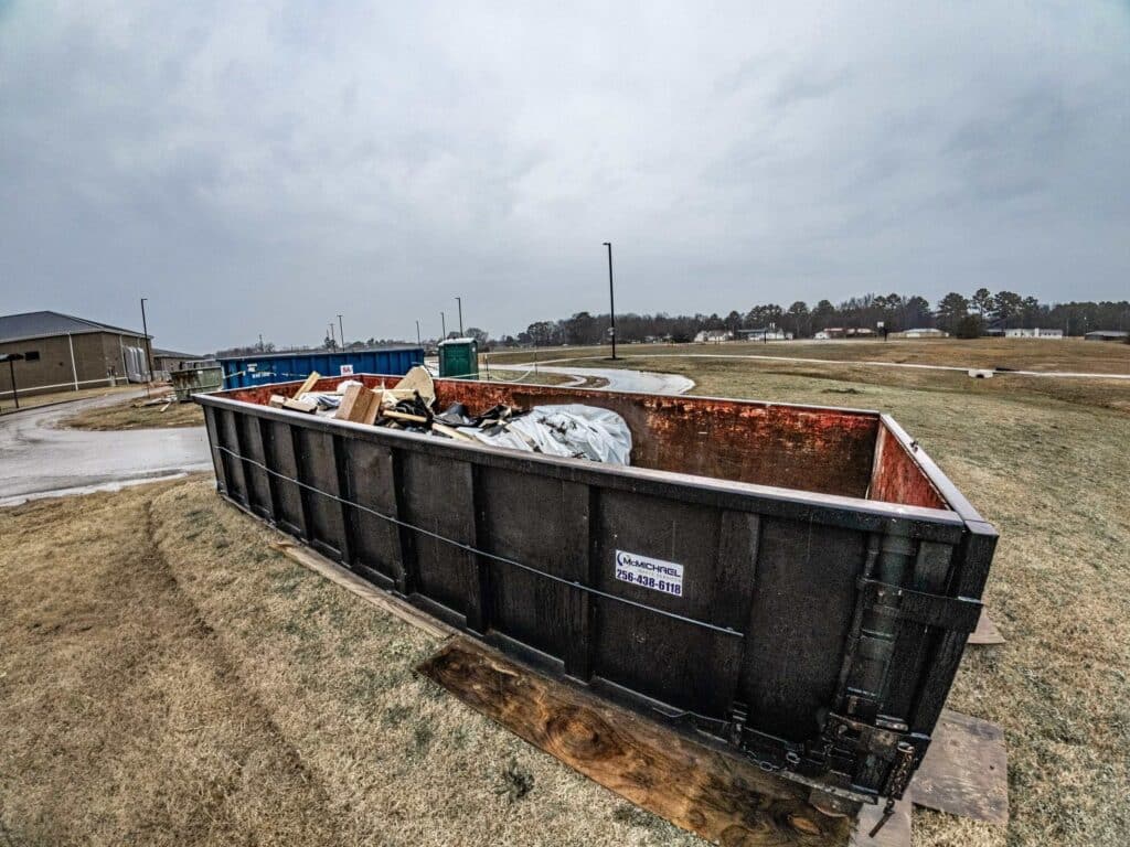 McMichael Waste Services roll-off container part-loaded with lumber and sheeting on an Alabama job site