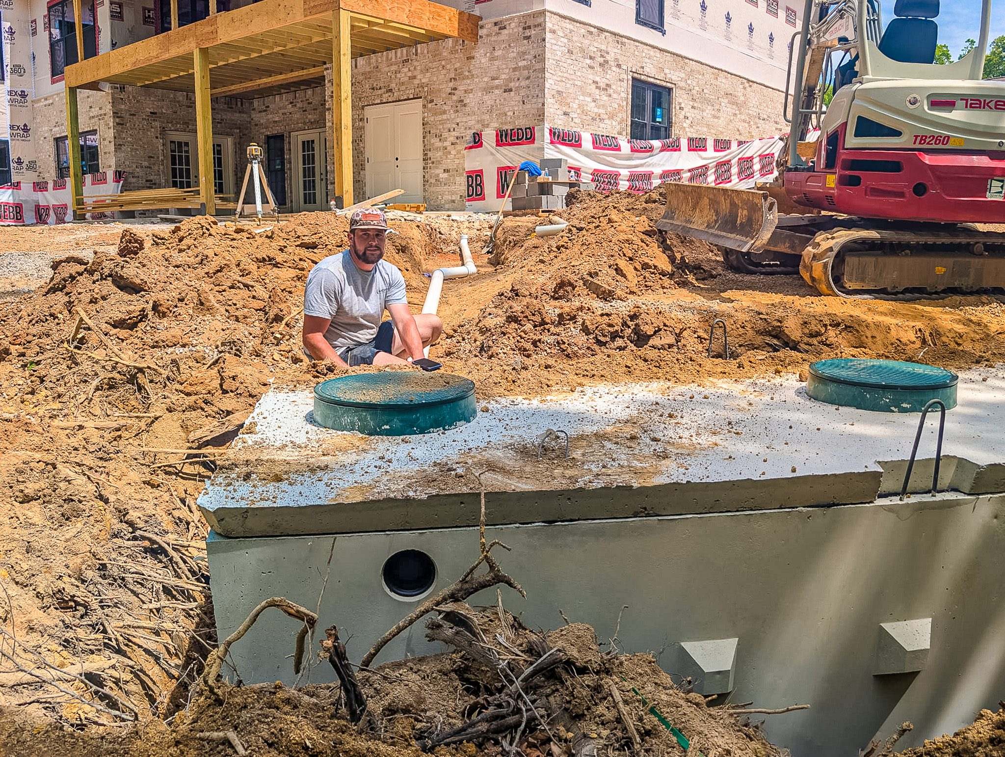 McMichael Waste Services crew installing a concrete septic tank with riser lids on a new-construction site in Alabama