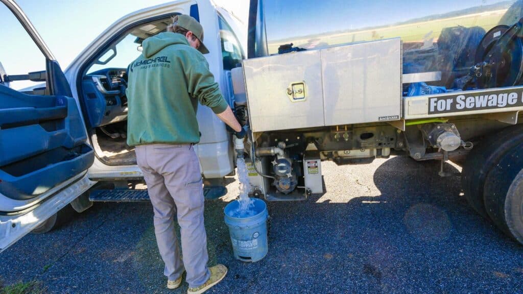 McMichael Waste Services crew member operating a drain valve at the vacuum truck in Alabama