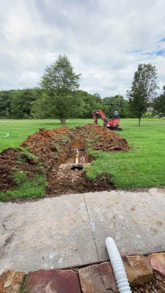 Trench excavated to a septic tank access lid in Alabama