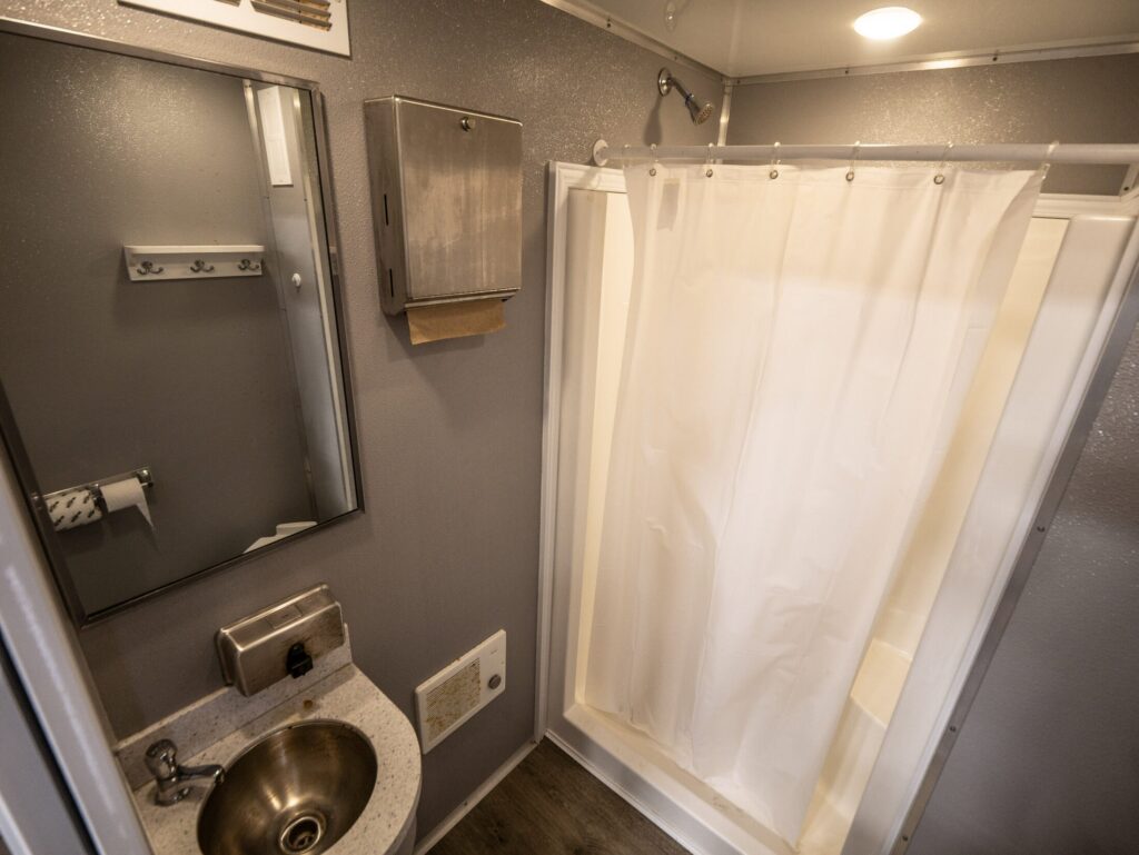 Interior of a McMichael Waste Services shower trailer stall with a private shower and vanity sink in Alabama