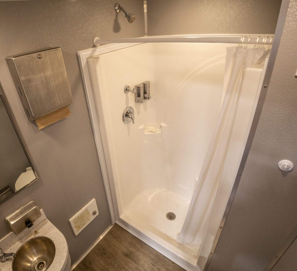 Interior of a McMichael Waste Services shower trailer with a walk-in shower stall and vanity in Alabama