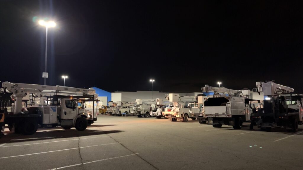 Storm response bucket trucks and equipment staged at night for deployment