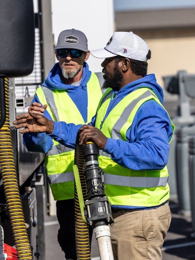 McMichael Waste Services crew members in safety vests working with a vacuum hose