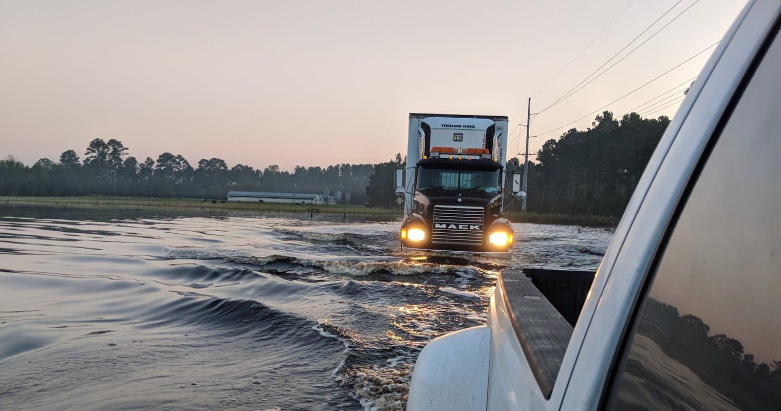 McMichael Waste Services trucks driving through a flooded road during storm response
