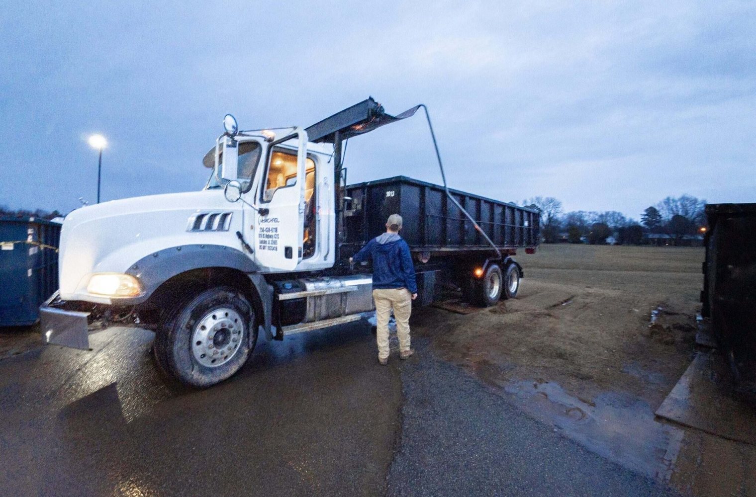 McMichael Waste Services roll-off driver beside his truck at the yard