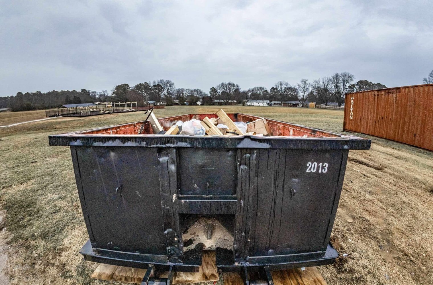 Loaded roll-off container set on plywood boards to protect the surface underneath