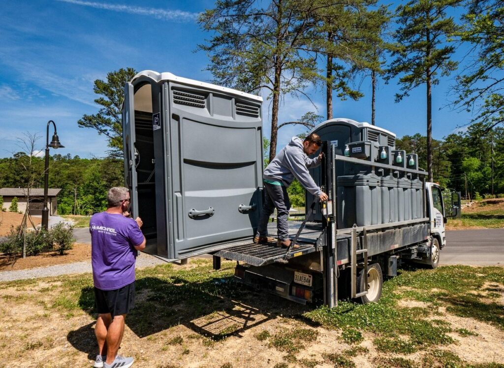 McMichael Waste Services crew unloading a portable toilet from a service truck