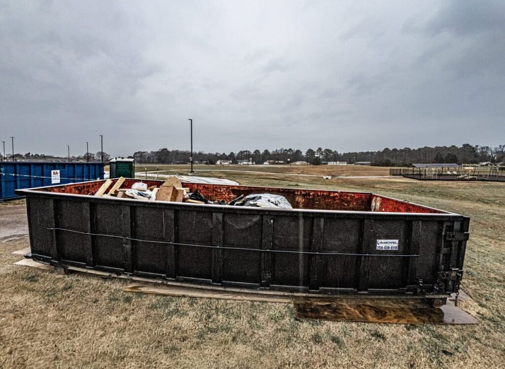 McMichael Waste Services roll-off dumpster loaded with debris on a jobsite