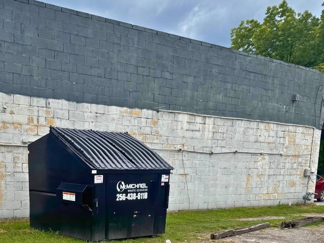 McMichael Waste Services front-load dumpster behind a commercial building in Alabama