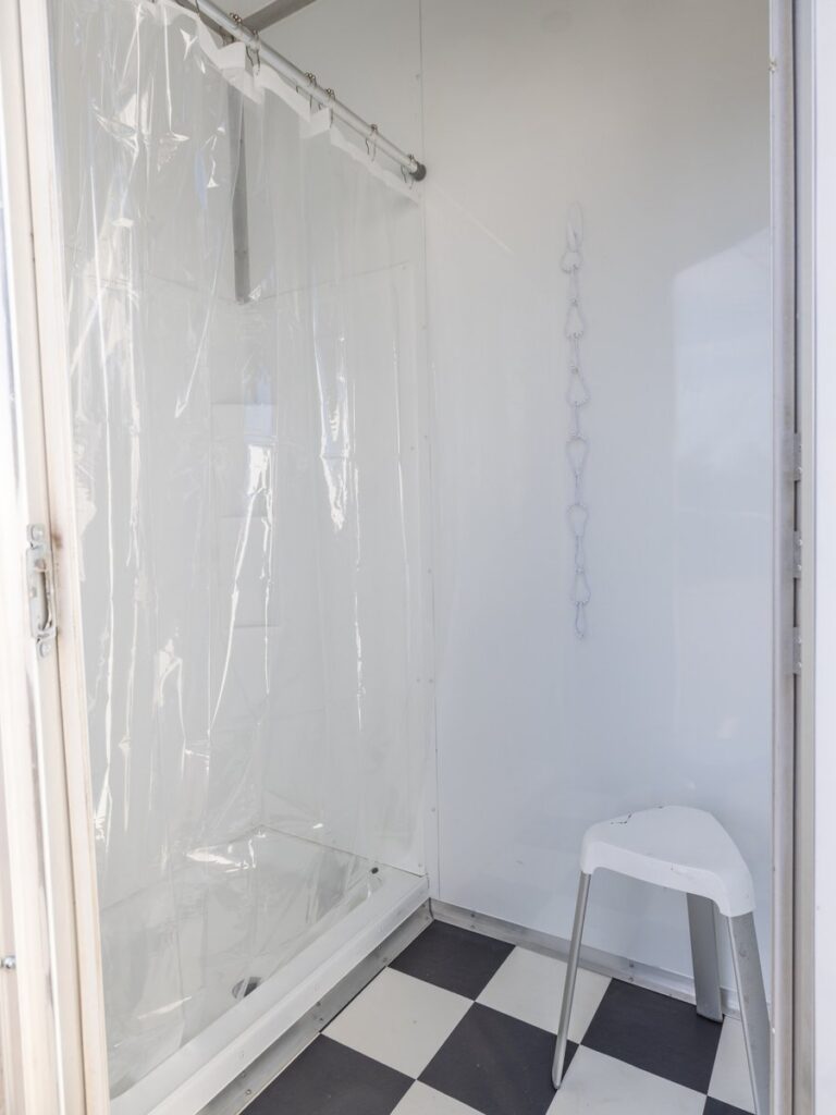 Shower trailer stall with a clear curtain, shower bench and checkered floor